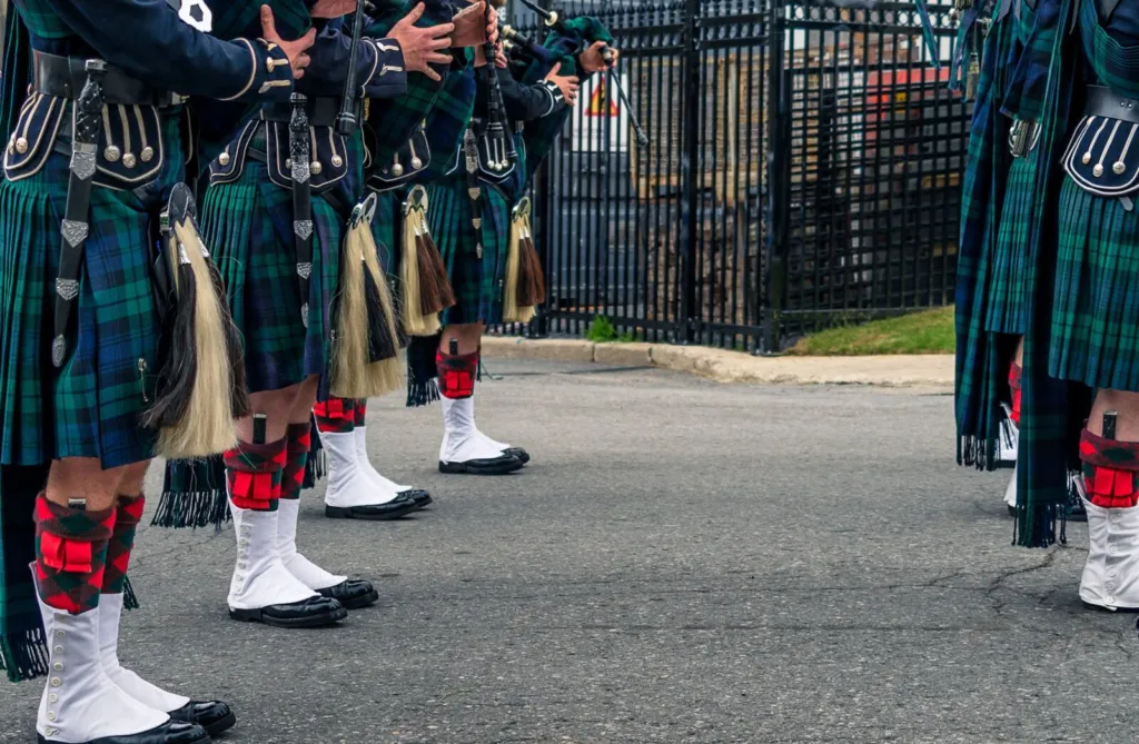 Caucasian men wearing the traditional Scottish kilt and playing